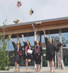 graduates tossing caps in front of a building