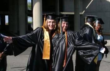 smiling graduates in black and gold regalia