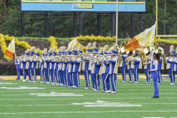 marching band in blue uniforms performing on field