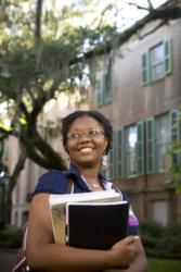 smiling student holding books outdoors