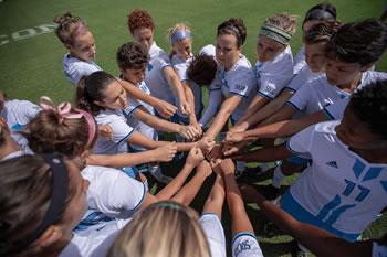 women's soccer team in a huddle on the field