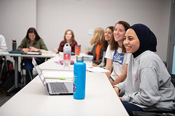 students smiling in class with laptops