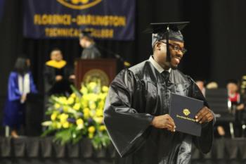 graduate smiling with diploma on stage