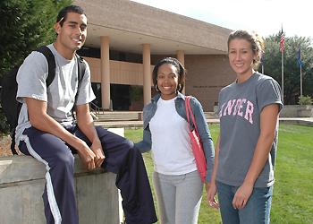 three students posing in front of a building