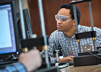 student in lab goggles working with equipment