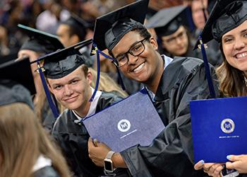 graduates holding diplomas and smiling