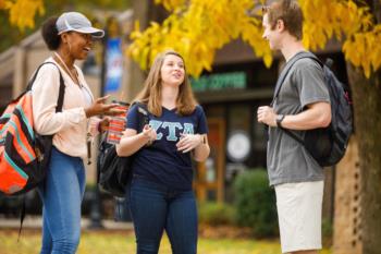 students conversing outside with fall foliage