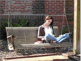 student reading on a wooden swing bench