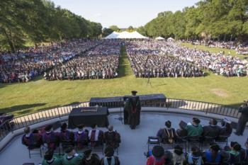 outdoor graduation ceremony with audience and faculty