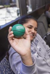 student holding a stress ball with 'upstate' logo