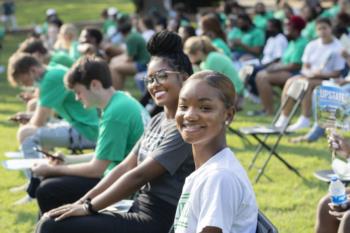 students in green shirts sitting on the grass