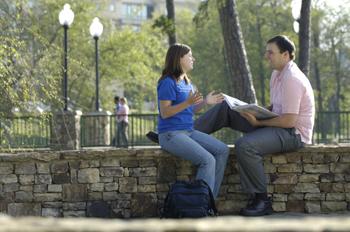 students in conversation on campus stone wall