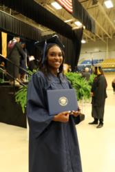 graduate holding a diploma, smiling at the camera