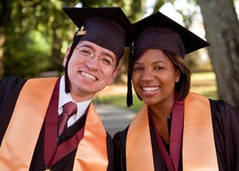 two graduates smiling in regalia