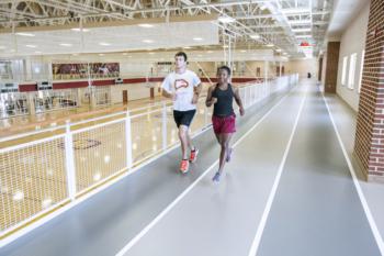 two students running on indoor track