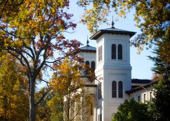 sunlit clock tower behind autumn trees