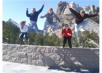 five people jumping in the air in front of a monument