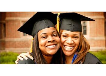 two graduates smiling and hugging