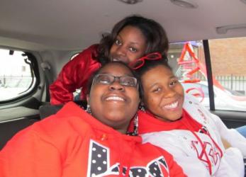 three people in red smiling inside a car