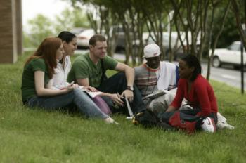 students sitting on grass in a campus setting