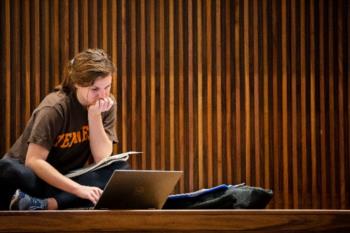 student studying with laptop in wood-paneled room