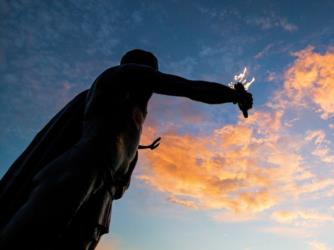 silhouette of a statue against sunset clouds