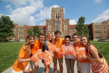 group of students with pom-poms in front of building