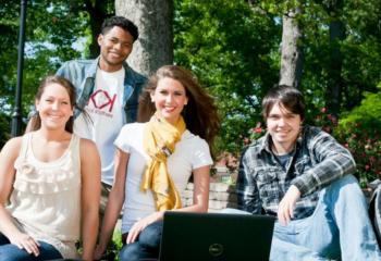 students with laptop sitting outdoors