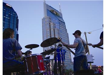 band performing in front of city skyline at dusk