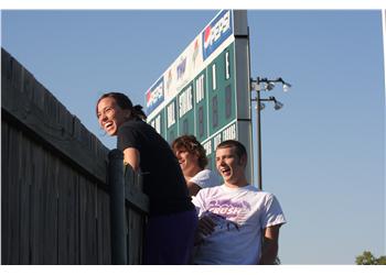 students on bleachers smiling over a fence