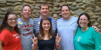 group of people smiling with hand signs