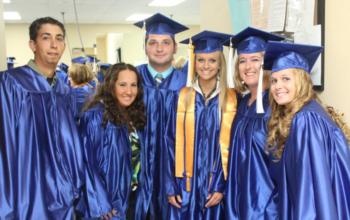 graduates smiling in blue caps and gowns