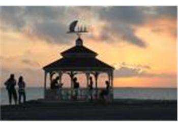 silhouettes at a beachfront pavilion at sunset