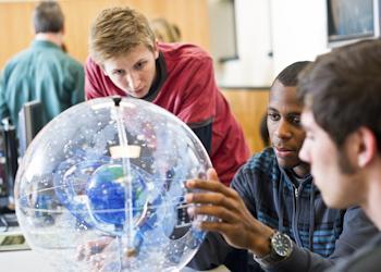 students inspecting a spherical model in a lab