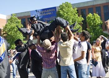 graduates tossing a peer in the air