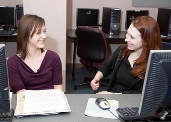 two students at computers discussing work