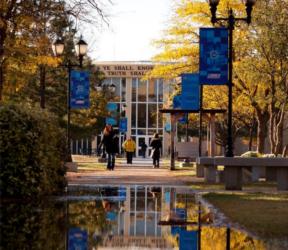 campus pathway with 'we shall know the truth' sign