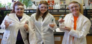 three women in lab coats conducting an experiment