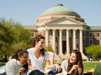 students studying on a lawn before a domed building