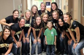 group of students smiling with a young boy