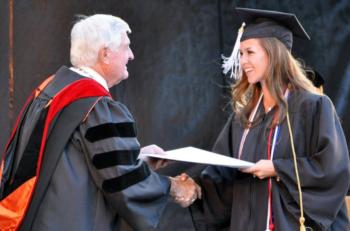 graduate receiving diploma from official