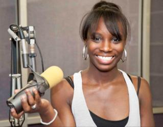 smiling person with microphone in a studio setting