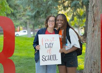 two students with 'first day school' sign