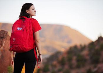 student with backpack looking at mountain