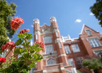 historic building with red brick and ornate towers behind flowers