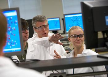 instructor discussing with students in a computer lab