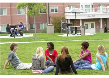 students sitting on grass in a campus green space