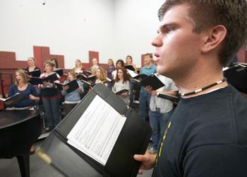 choir rehearsal with male student holding music sheet