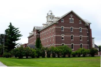 old brick building with clock tower and lawn