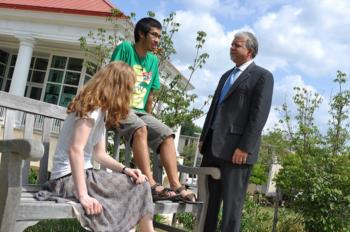 three people having a conversation on campus benches